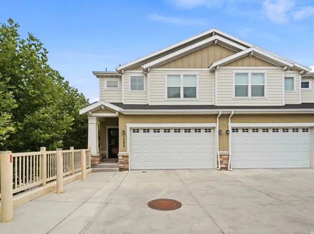 Two-story exterior with multi-pane windows, dual garage doors, a covered entry, and a concrete driveway