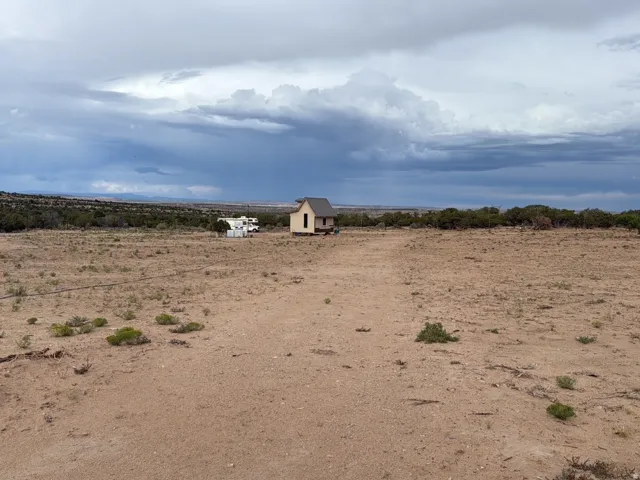 Expansive undeveloped land with a small structure and distant trees