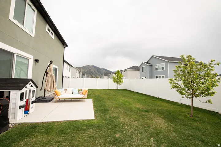 Expansive backyard featuring a concrete patio, a manicured lawn, and a white privacy fence