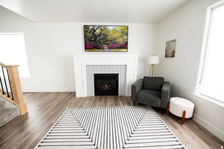Wood-finish flooring, white walls, and a fireplace with a decorative tile surround and white mantel