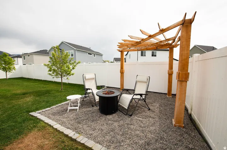 Gravel patio area with a wooden pergola, bordered by a white privacy fence