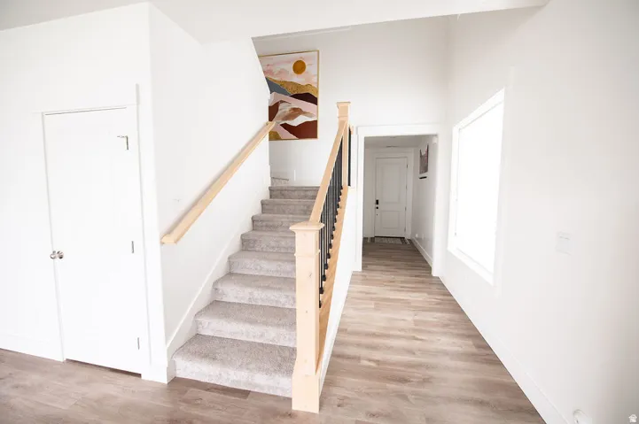 Staircase featuring carpeted treads, wood handrail, and wrought iron balusters