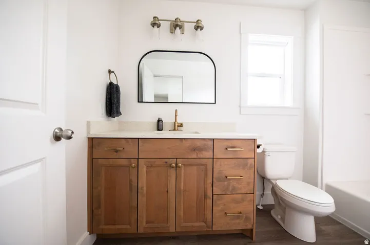 Wood-finish flooring with a white bathtub and toilet