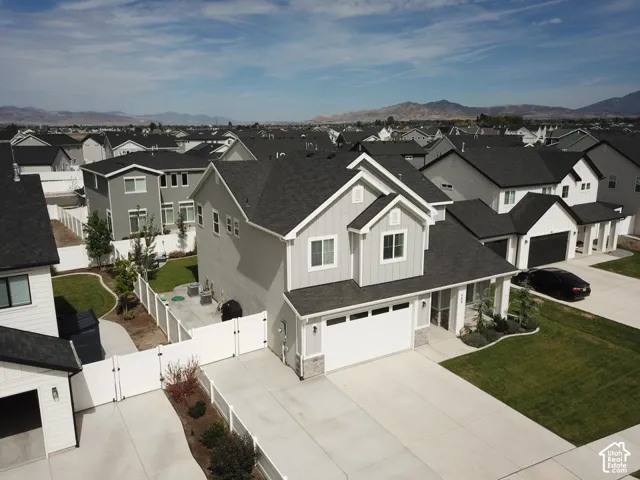Contemporary residence featuring a two-car garage, concrete driveway, and a white fence enclosing a landscaped yard