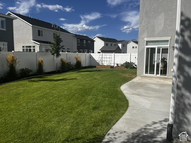 Expansive lawn with a perimeter fence, mature landscaping, and a concrete patio