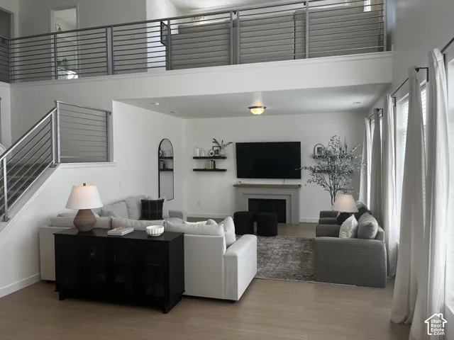 Vaulted ceiling featuring a loft with metal railing, wood-finish flooring, a fireplace with a mantel, and recessed lighting