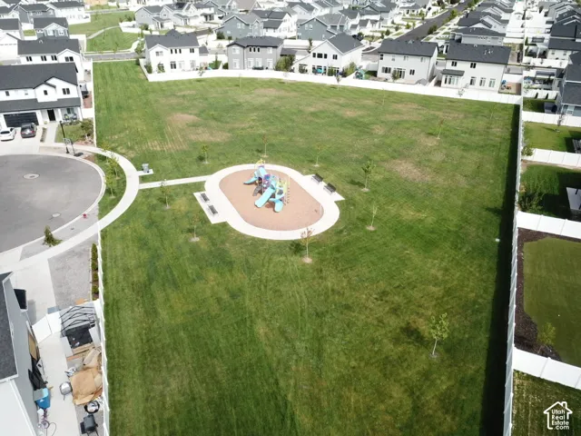 Expansive green space featuring a central playground, paved pathways, and mature trees