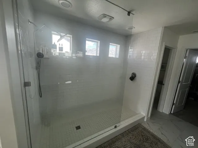 Spacious walk-in shower with clear glass enclosure and white subway tile surround