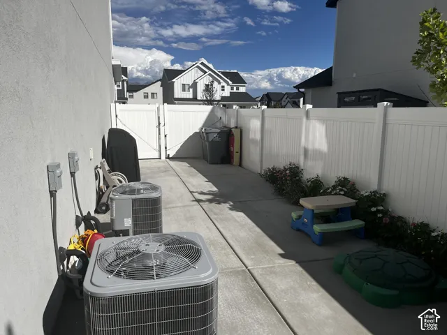 Concrete paving extending to a white privacy fence with a gated entry