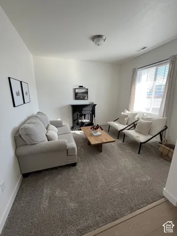 Recessed corner fireplace with a black mantel, wall-to-wall carpeting, and a window with blinds