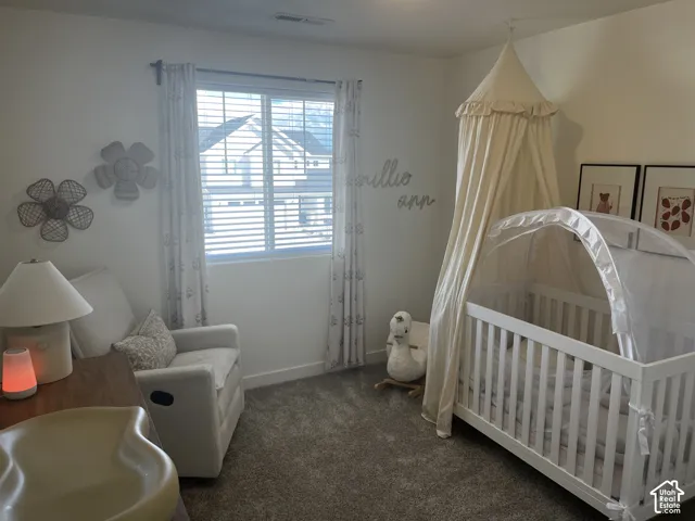 Carpeted room featuring a window with horizontal blinds, drapes, and white walls