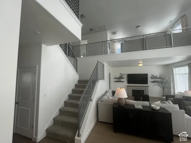 Two-story interior with an open-concept layout, featuring a staircase with horizontal metal railings, a spacious main living area, and an upper-level landing with matching railings