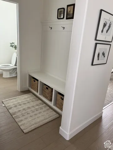 Built-in storage bench with three open compartments, integrated wall paneling, and two coat hooks
