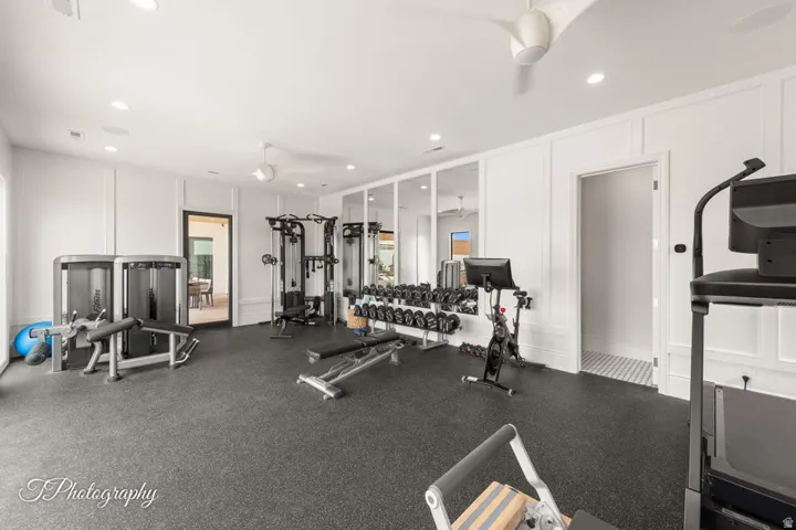Dedicated fitness room featuring rubber flooring, recessed lighting, and paneling on walls
