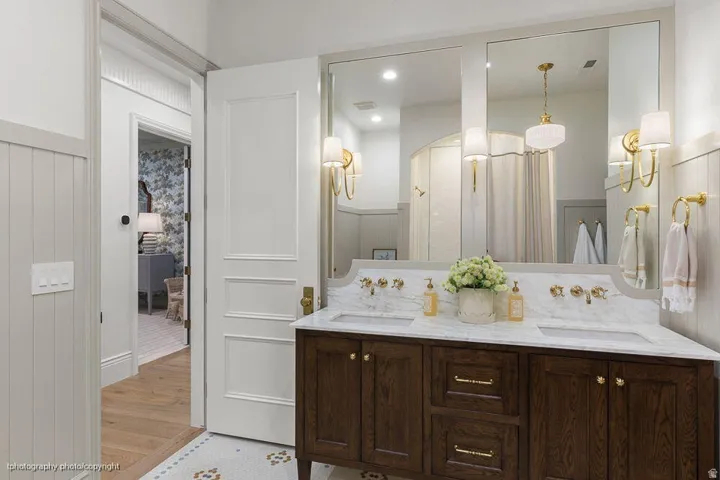 Double vanity with a white stone countertop and brass wall-mounted faucets