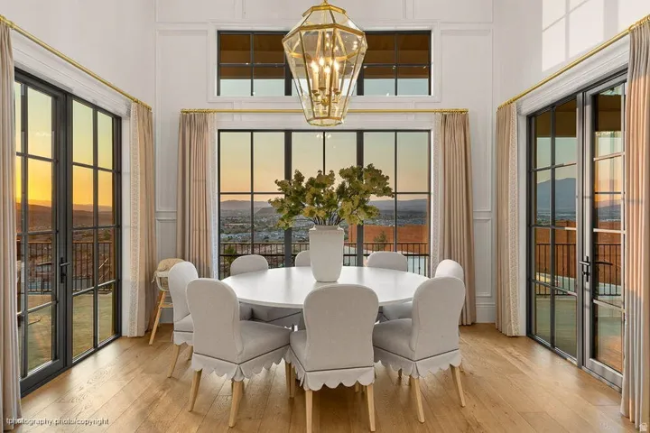Hardwood flooring, floor-to-ceiling multi-pane doors, transom windows, high vaulted ceiling, and an ornate pendant light fixture