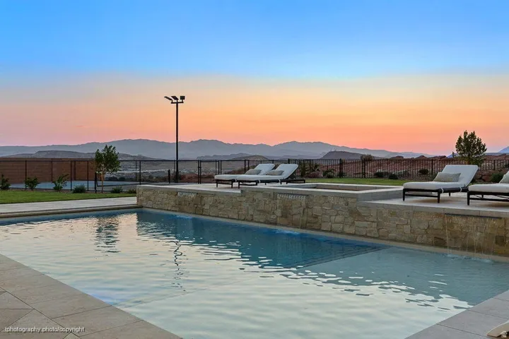 Swimming pool with stone-clad retaining wall, integrated spa, and tiled coping