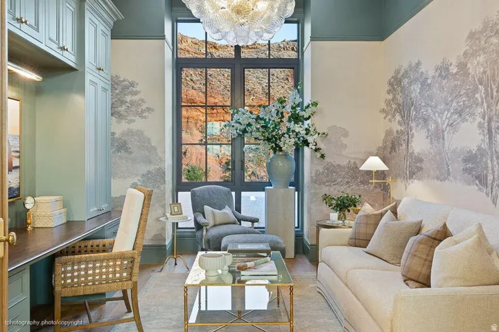 Built-in cabinetry with task lighting, wood-finish desktop, floor-to-ceiling multi-pane window, decorative wall mural, and crown molding