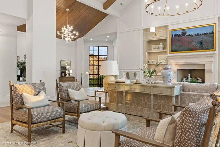 Vaulted wood-paneled ceiling, large fireplace with mantel, built-in shelving, hardwood flooring, and a large iron-framed window