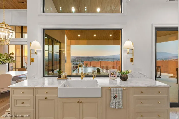 White farmhouse sink with a brass faucet, set within a light-toned cabinetry island