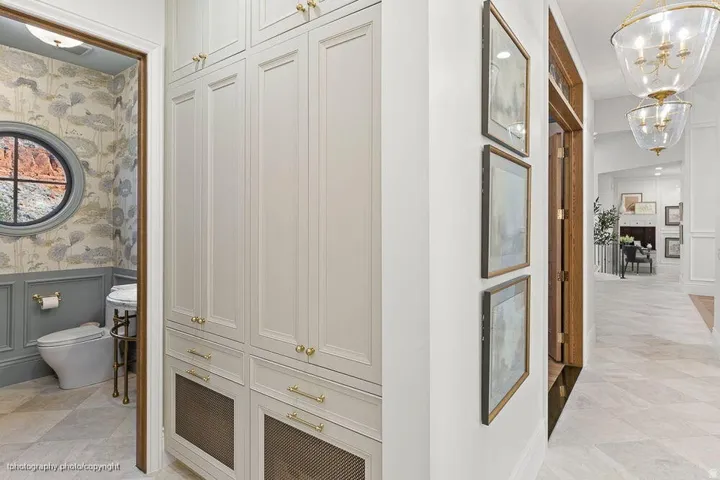 Built-in cabinetry with gold-toned hardware, round window, wall paneling, and chevron pattern flooring