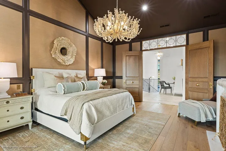 Vaulted ceiling with a chandelier, wood-finish flooring, paneled wall detailing, and double wooden doors with an overhead transom window