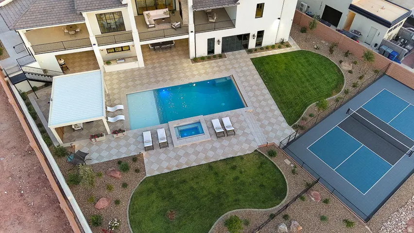 Expansive rear exterior featuring a swimming pool, integrated spa, covered patio, and a dedicated sports court