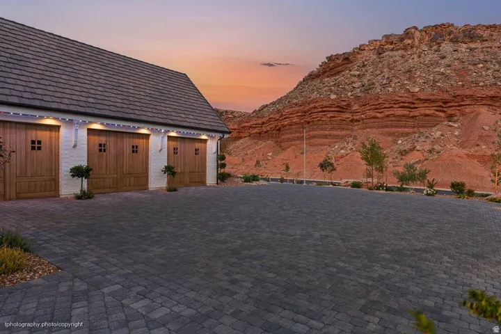 Three-car garage with wood panel doors and a shingled roof