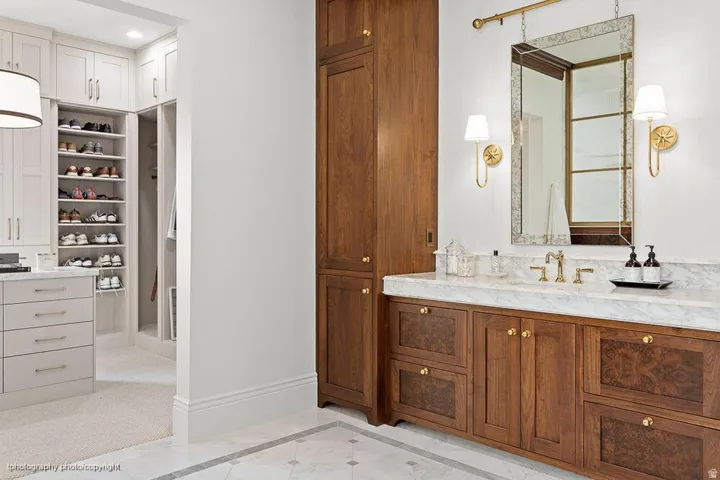 Wood-finish vanity with a light-toned countertop, brass hardware, and a framed mirror