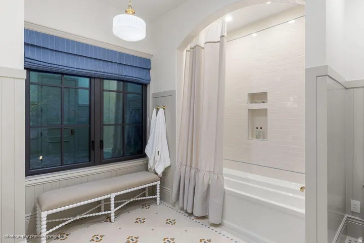 Arched shower alcove with tiled walls, built-in recessed shelves, and a white bathtub