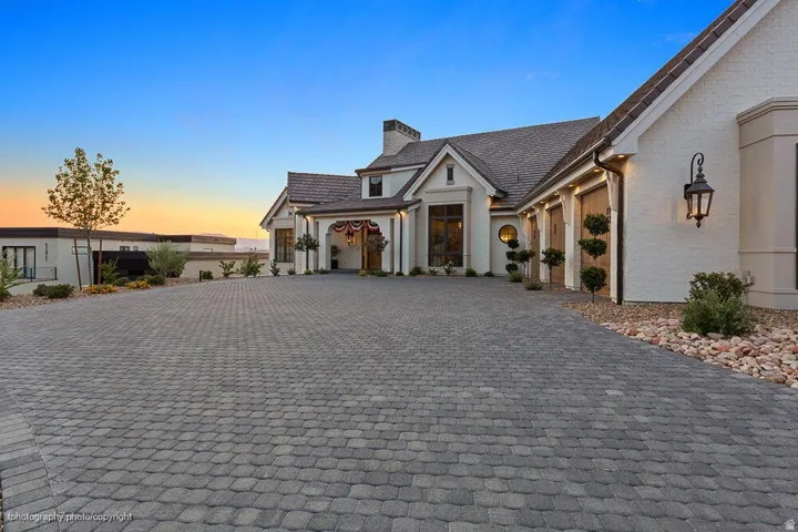 Expansive paver driveway leading to a multi-car garage with wood-finish doors