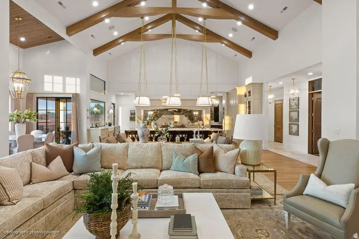 Vaulted ceilings with exposed wood beams, wood-finish flooring, recessed lighting, and multiple pendant light fixtures