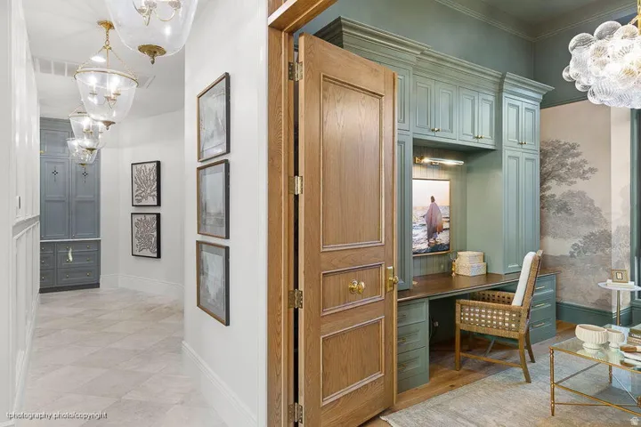 Wood-paneled door with brass hardware, custom built-in cabinetry, wood-finish flooring, recessed lighting, and wall-mounted light fixtures
