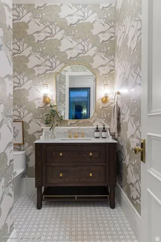 Dark wood-finish vanity with a stone countertop, featuring a gold-finish faucet and hardware