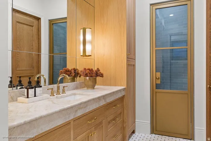 Vanity with an integrated sink, polished brass fixtures, and a natural stone countertop