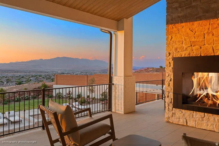 Covered outdoor patio with a built-in fireplace featuring a stone surround, tiled flooring, and a slatted wood ceiling