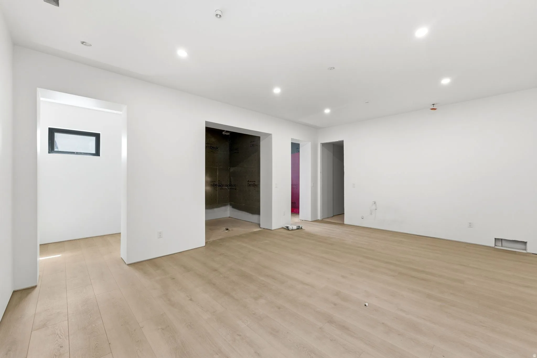 Recessed lighting, wood-finish flooring, white walls, multiple doorways, and a rectangular window