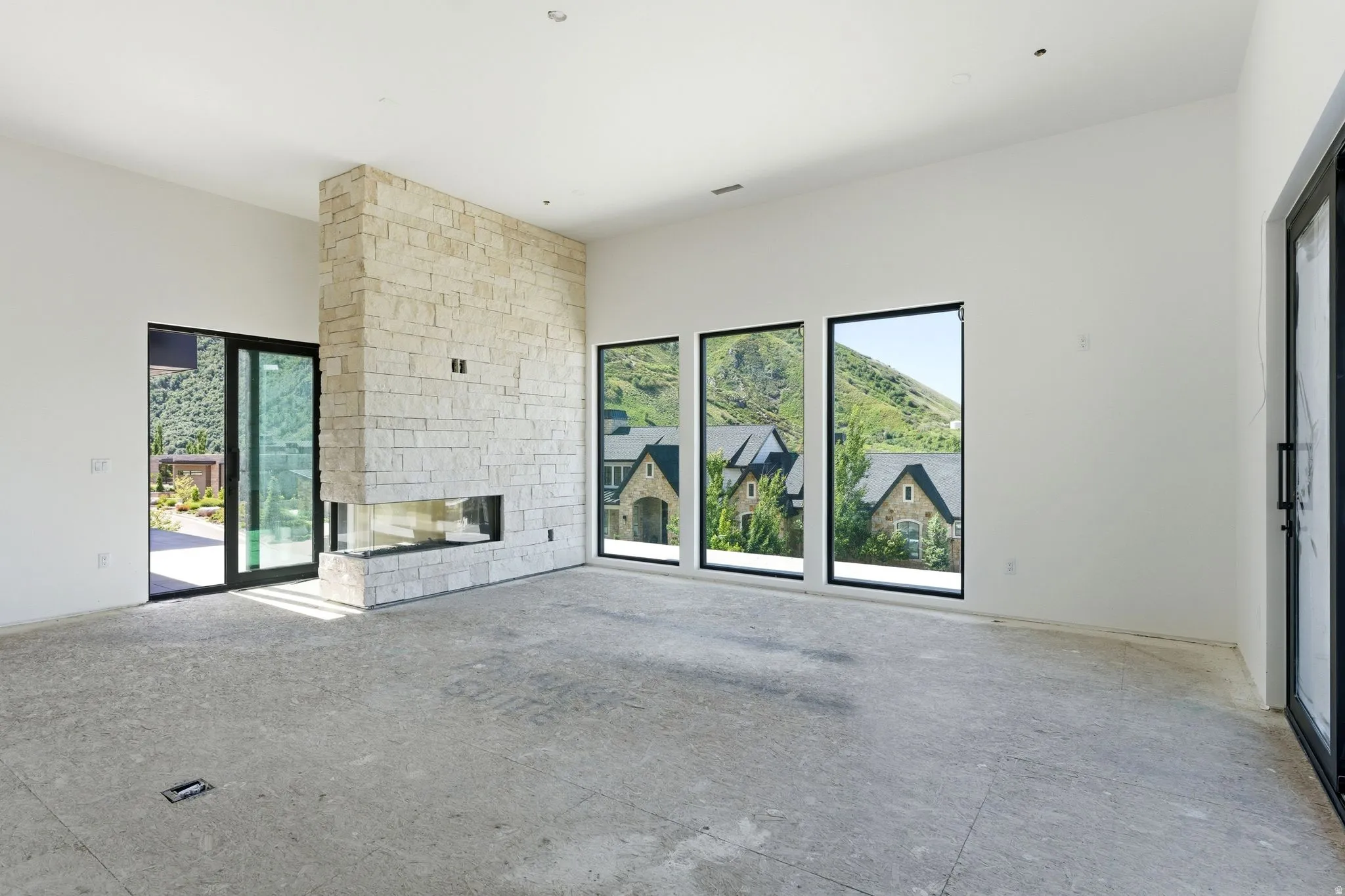 Stacked stone fireplace with a linear insert, full-height windows, and a sliding glass door