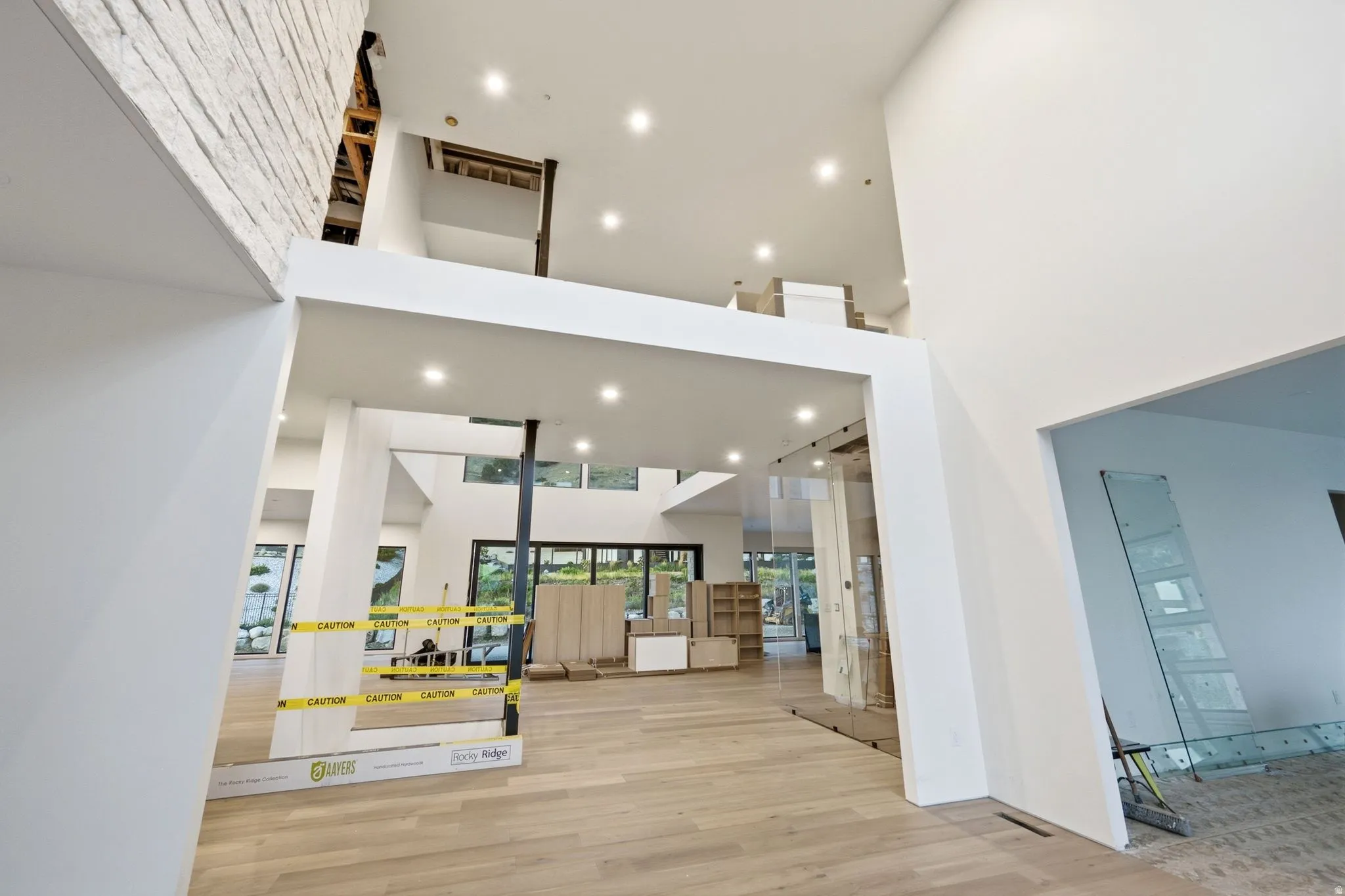 Two-story interior with recessed lighting, light wood-finish flooring, and a glass-paneled barrier