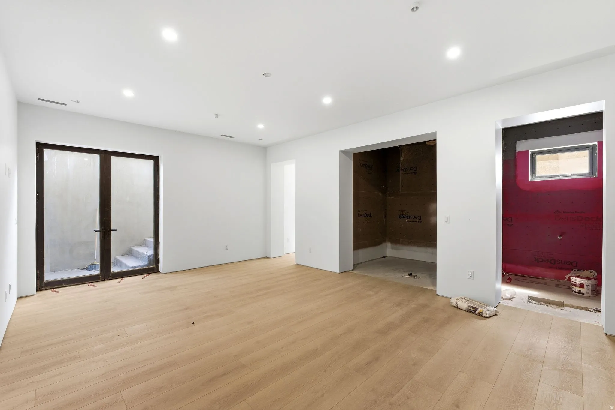Recessed lighting, wood-finish flooring, white walls, and dark-framed double doors