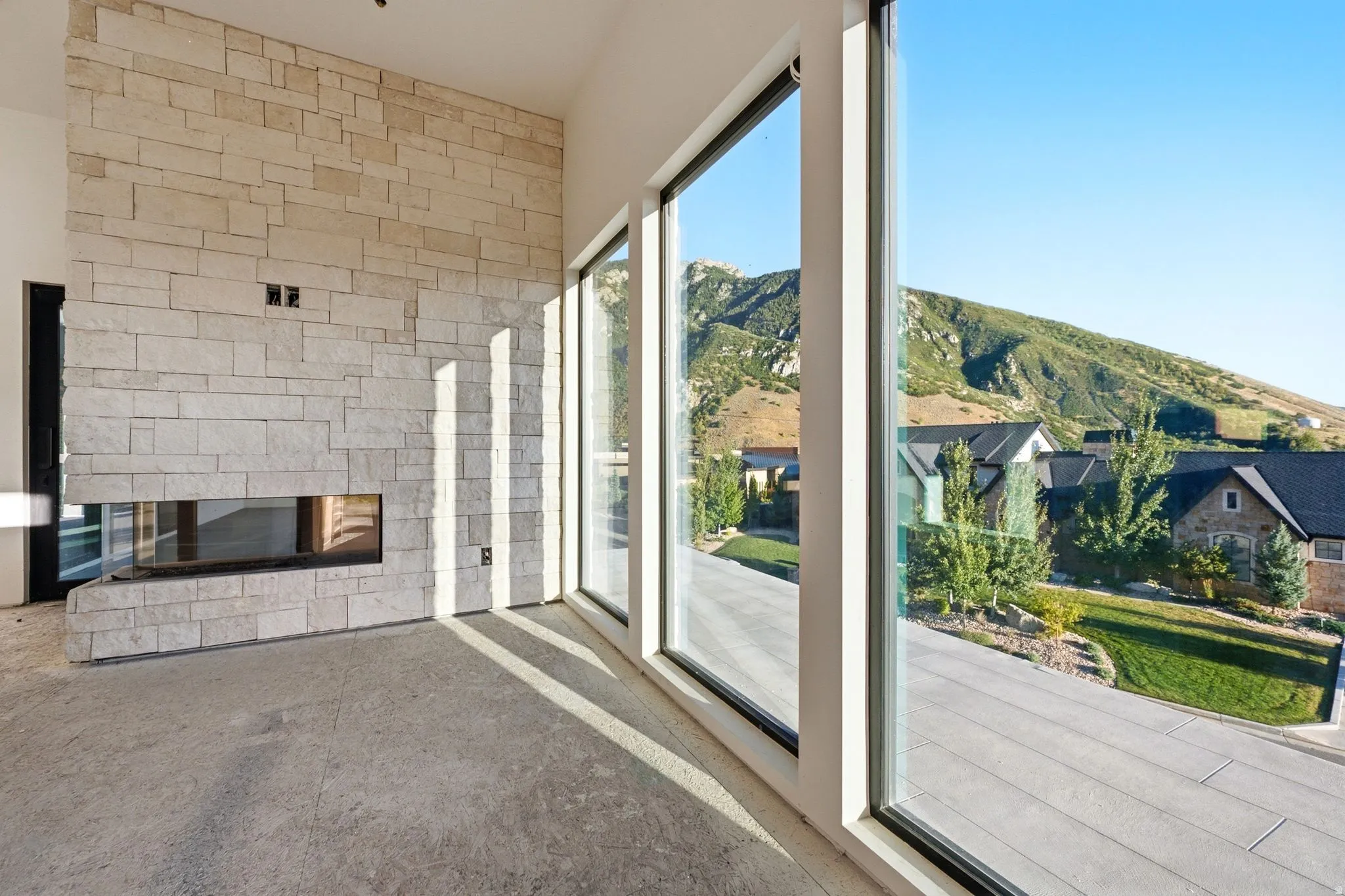 Stone-clad fireplace with a linear firebox, large floor-to-ceiling windows, and mountain scenery