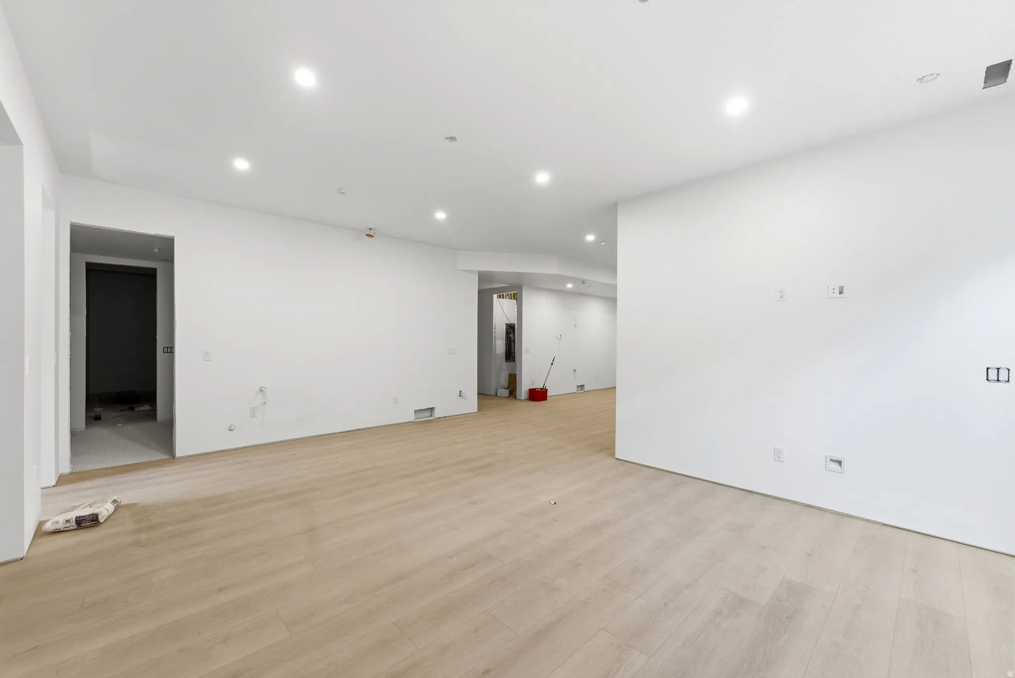 Recessed lighting, light wood-finish flooring, and white walls