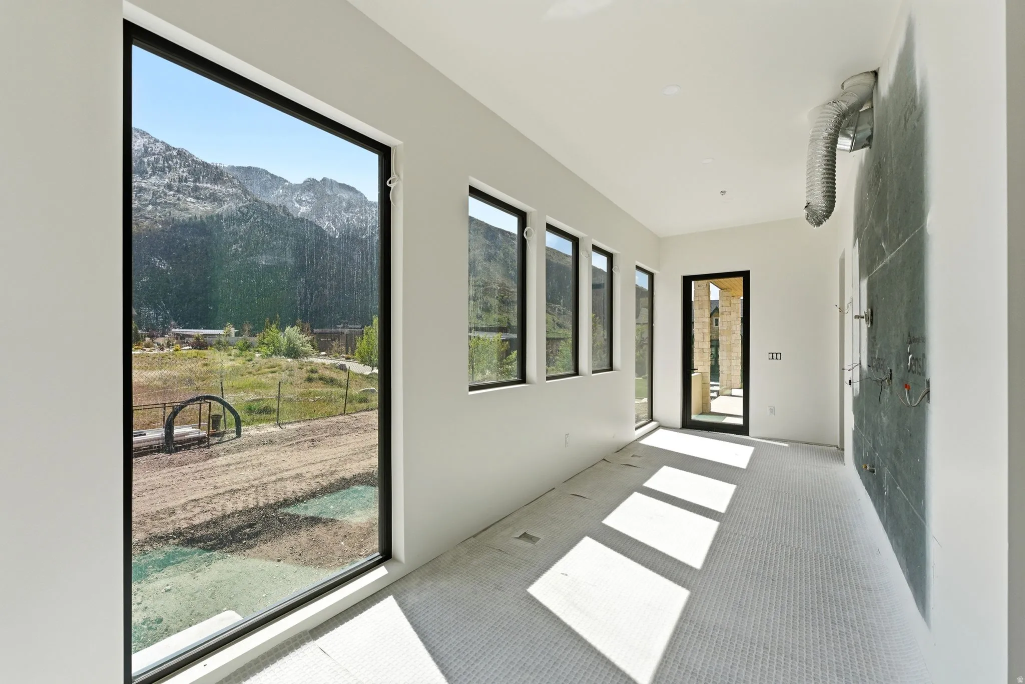 Floor-to-ceiling windows, multiple transom windows, full-light exterior door with dark frame, textured wall paneling, and wall-mounted plumbing fixtures