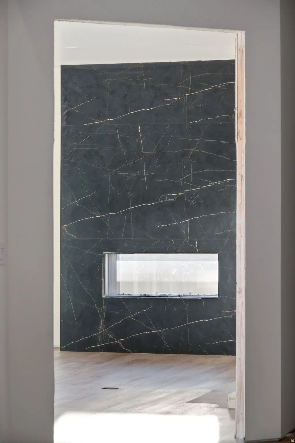 Black marble-look tile accent wall with gold veining, featuring a rectangular built-in electric fireplace