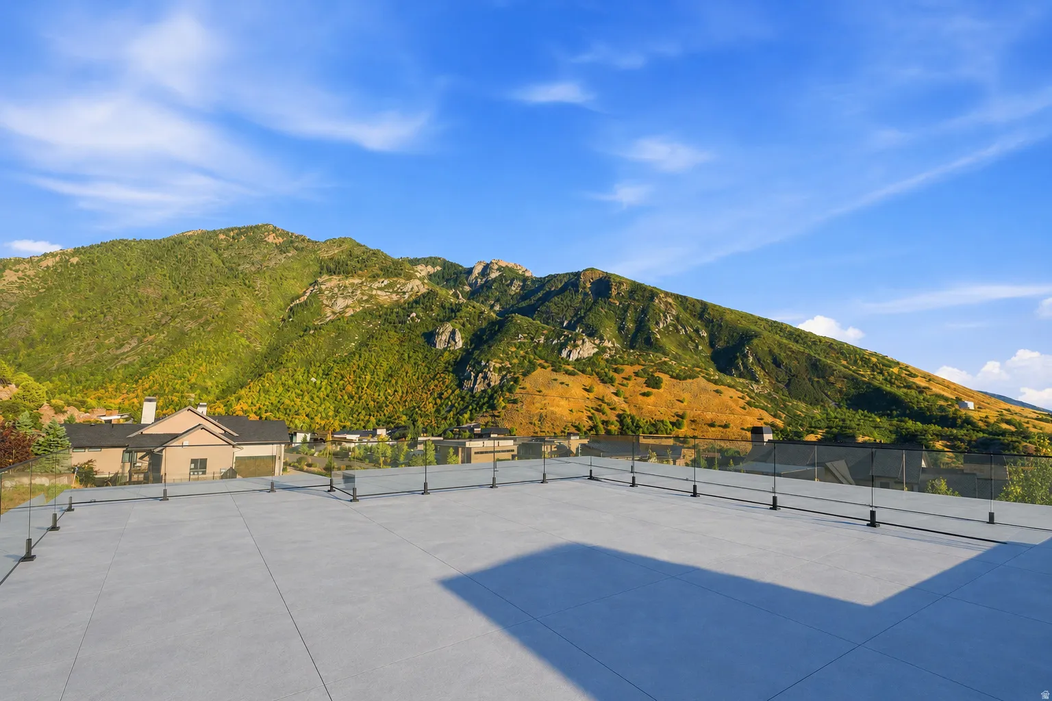 Expansive rooftop deck with mountain scenery and glass panel railing