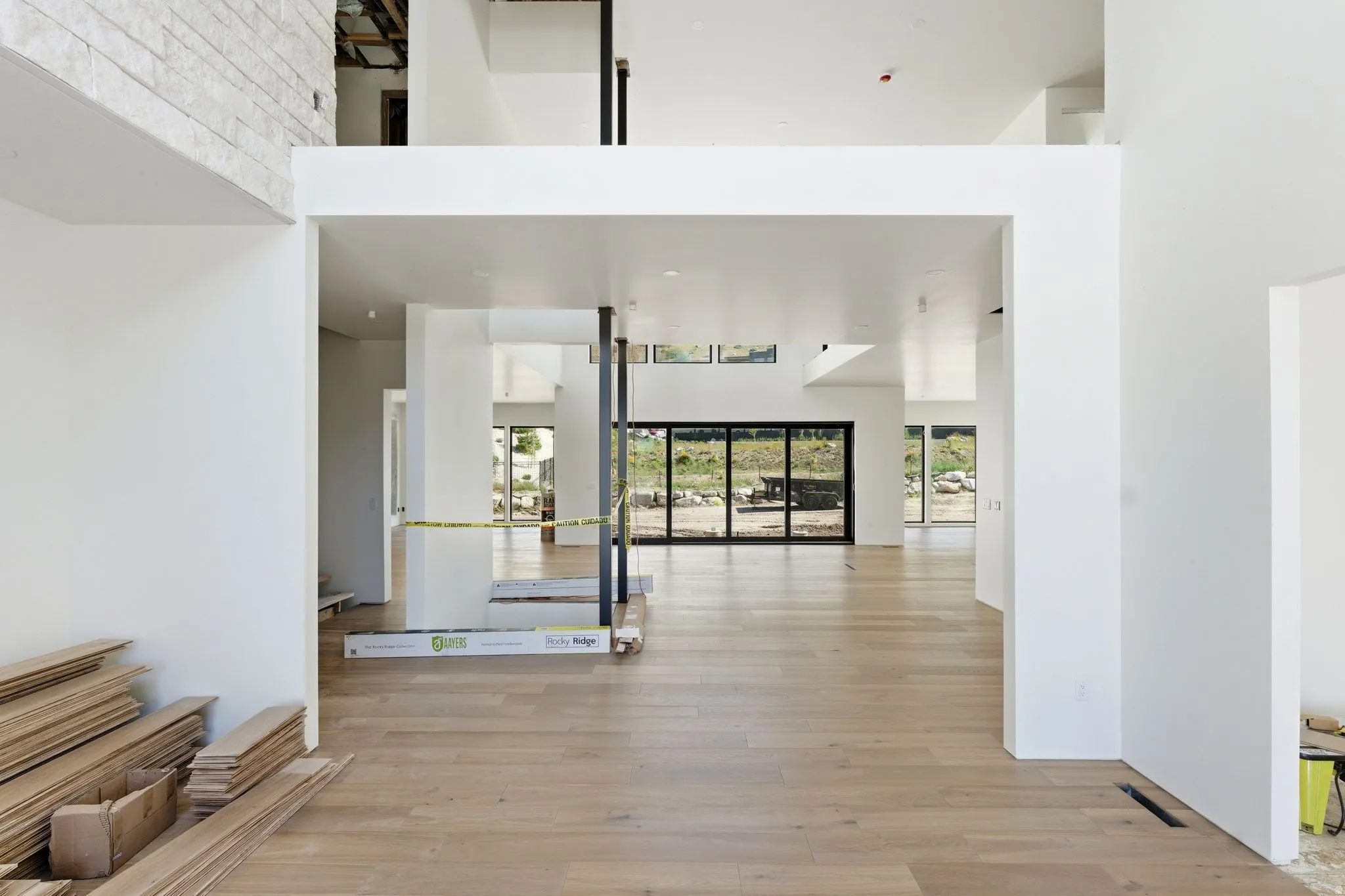 Open-concept interior featuring wood-finish flooring, white walls, and a multi-level ceiling