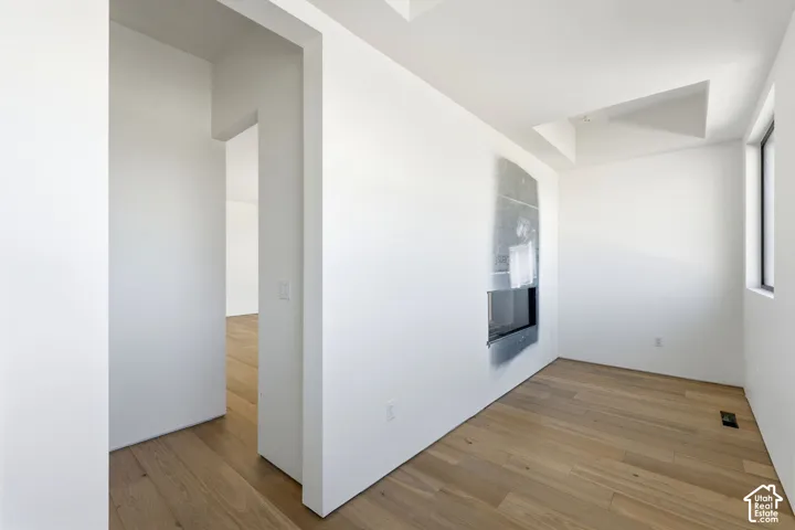 Interior space featuring wood-finish flooring, recessed ceiling lighting, and a modern wall-integrated fireplace with a stone-finish surround