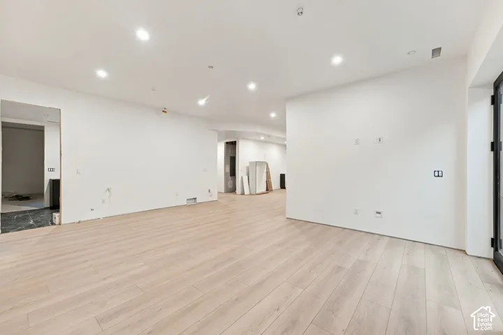 Open-concept interior featuring light-toned wood-finish flooring, recessed ceiling lighting, and matte black door framing