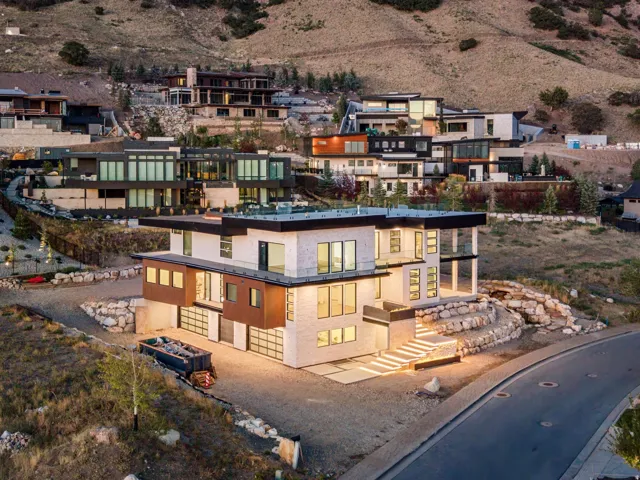 Modern architectural design featuring multi-level construction, extensive window placements, multiple garage doors, and illuminated exterior steps