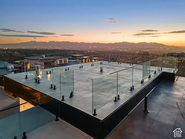 Spacious rooftop terrace featuring glass railings and a mountain backdrop with cityscape beyond